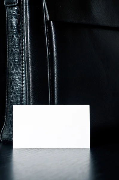 Біла листівка для письма з чорною шкіряною сумкою на столі — стокове фото