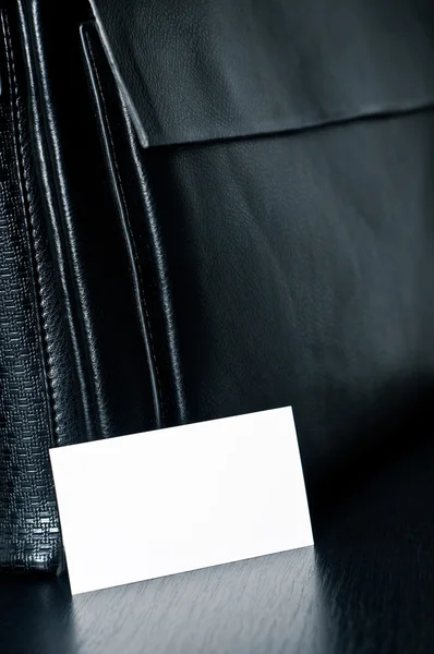 Biała kartka do pisania z czarną skórzaną torbą na stole — Zdjęcie stockowe