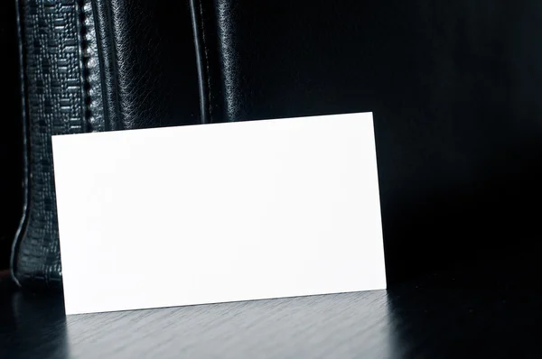 Witte kaart om te schrijven met zwarte leren tas op tafel — Stockfoto