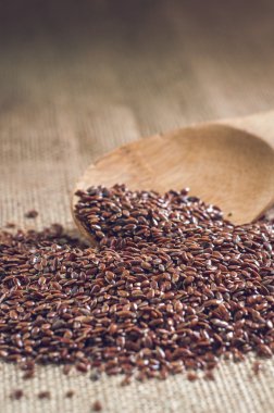 çuval bezi arka plan üzerine bir tahta kaşıkla keten tohumu