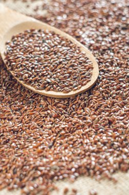 çuval bezi arka plan üzerine bir tahta kaşıkla keten tohumu