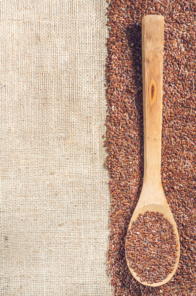 flax seeds with a wooden spoon on burlap background