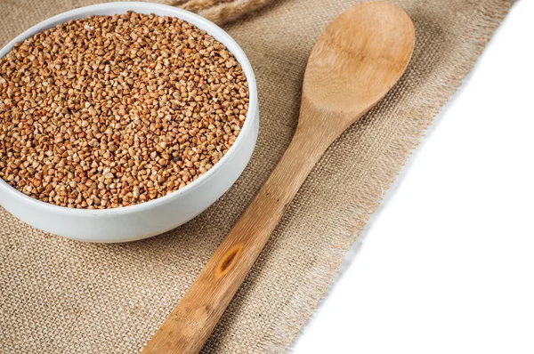 Buckwheat and wooden spoon on burlap background. isolate — Stock Photo, Image