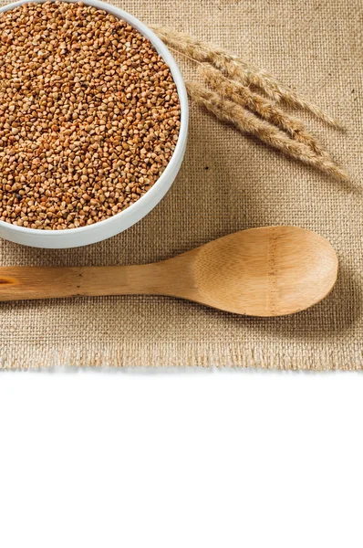 Buckwheat and wooden spoon on burlap background. isolate — Stock Photo, Image