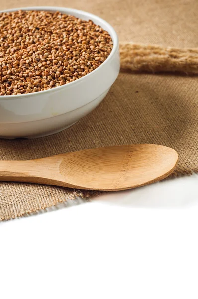 Buckwheat and wooden spoon on burlap background. isolate — Stock Photo, Image