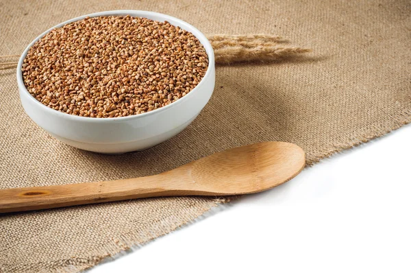 Buckwheat and wooden spoon on burlap background. isolate — Stock Photo, Image