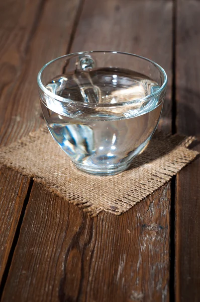 Glasbecher mit Wasser auf einem Hintergrund aus Klecksen — Stockfoto