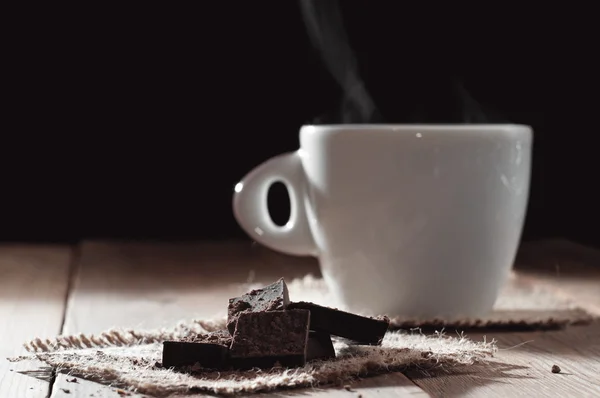 Чашка кофе с шоколадом на деревянный стол и черный фон — стоковое фото