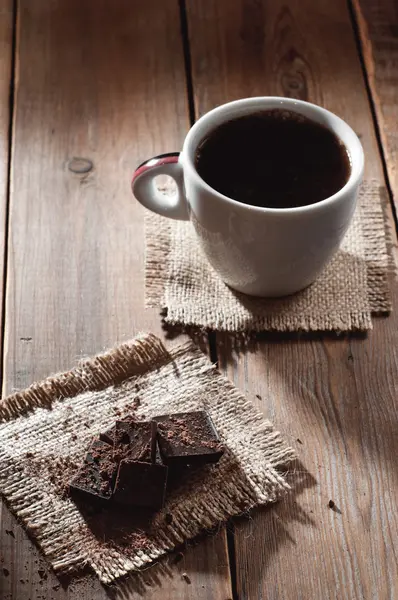 杯咖啡与巧克力木桌和黑色背景 — 图库照片