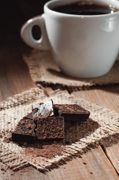 Tasse café avec chocolat sur table en bois et fond noir — Photo