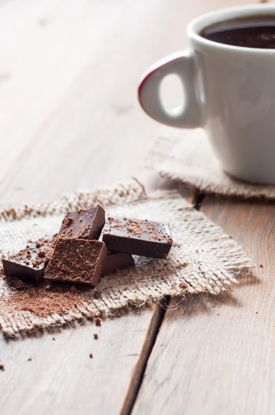 Tasse café avec chocolat sur table en bois et fond noir — Photo