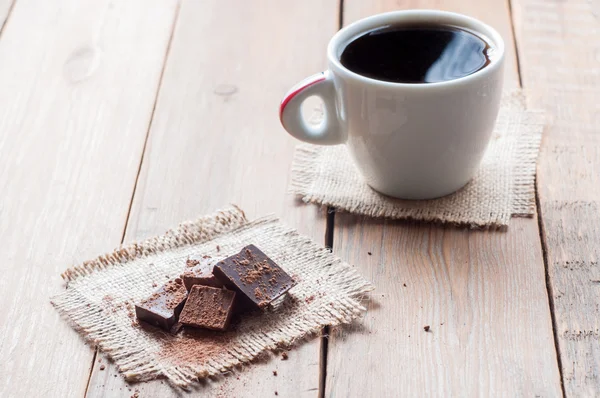 Tasse café avec chocolat sur table en bois et fond noir — Photo