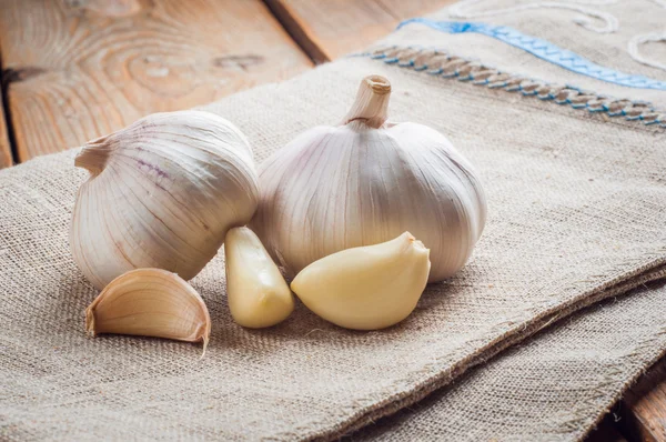 Szerves fokhagyma egészben és szegfűszeg a fa háttér — Stock Fotó