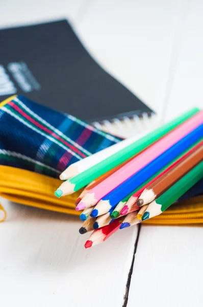 Schetsboek en kleurrijke potloden op tafel — Stockfoto