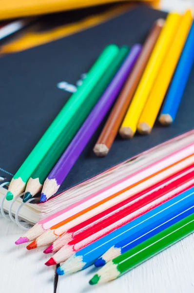 Cuaderno de bocetos y lápices de colores sobre la mesa — Foto de Stock