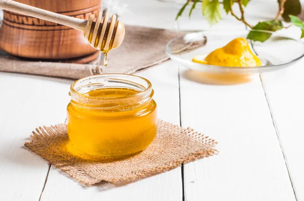 Vaso di miele con scanalatura e limone che scorre, fondo di legno — Foto Stock