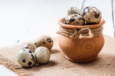 çuval bezi arka plan üzerinde ahşap bir kapta çiğ bıldırcın yumurtası