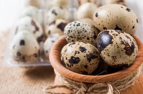 Huevos de codorniz crudos en un tazón de madera sobre fondo de arpillera — Foto de Stock