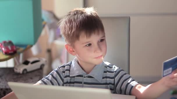 Netter kleiner Junge benutzt Laptop und Kreditkarte — Stockvideo