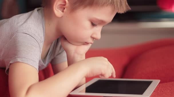 Маленький мальчик играет на планшетных компьютерных играх — стоковое видео