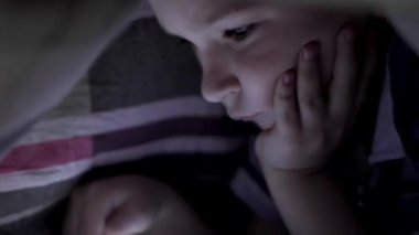 Oğlum battaniyenin altında yalan ve çizgi film izlerken dokunmatik yüzey