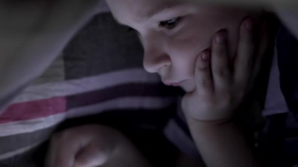 Chłopiec leżącego pod koc i oglądanie kreskówek na touch pad — Wideo stockowe