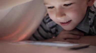 Oğlum battaniyenin altında yalan ve çizgi film izlerken dokunmatik yüzey