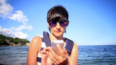 Deniz arka plan üzerinde cep telefonu kullanan genç kadın