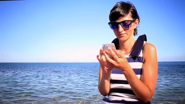 Giovane donna che utilizza il cellulare sullo sfondo del mare — Video Stock