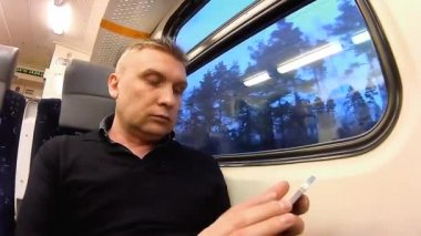Adam bir smartphone bir yolcu treni bir kompartımanda kullanır.