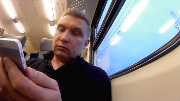 Homem usa um smartphone em um compartimento de um trem de passageiros — Vídeo de Stock