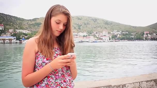 Kız kullanma smartphone deniz arka plan üzerinde — Stok video