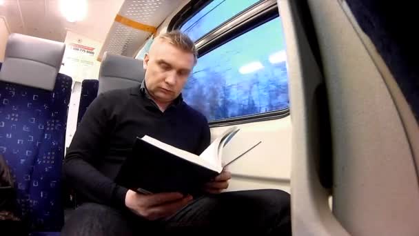 Hombre leer libro en un tren de pasajeros — Vídeos de Stock