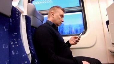 Adam bir smartphone bir yolcu treni bir kompartımanda kullanır.