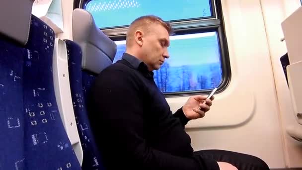 Man gebruikt een smartphone in een compartiment van een passagierstrein — Stockvideo