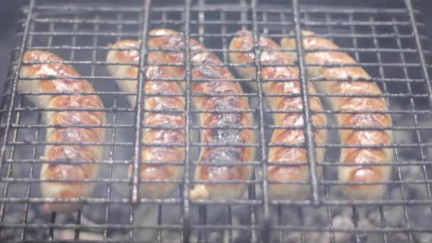 Salchichas Bratwurst cocinando en una barbacoa de madera . — Vídeo de stock