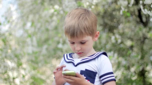 Jeune garçon joue à des jeux sur smartphone. Parc de printemps 