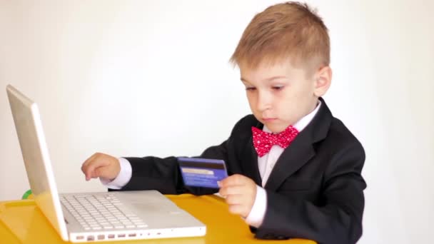 Милий маленький діловий хлопчик використовує ноутбук і кредитну картку — стокове відео