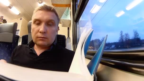 列車の旅の本を楽しんで男 — ストック動画