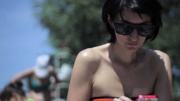 Jeune femme utilisant un smartphone sur la plage — Video