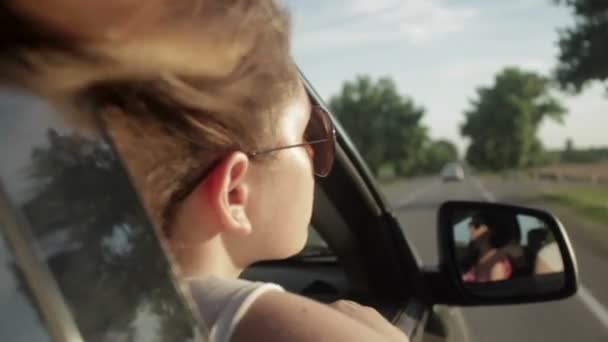 Wind weht durch Mädchenhaare in einem Auto. Sonnenuntergang — Stockvideo