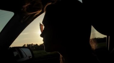 Rüzgar üfleme ile kızlar siluet ve saç bir arabanın içinde. Günbatımı