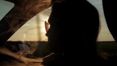 Rüzgar üfleme ile kızlar siluet ve saç bir arabanın içinde. Günbatımı