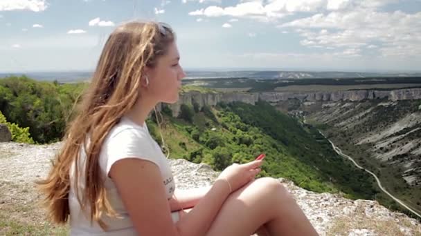 Teenager-Mädchen hört Musik mit Kopfhörern auf Smartphone vor Bergkulisse — Stockvideo