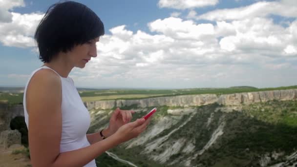 Donna attraente che scrive su smartphone su uno sfondo di montagne — Video Stock