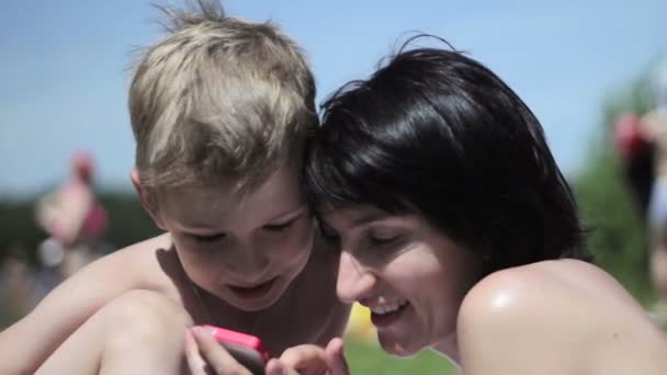 Mom and son at a beach playing with a smartphone — Stock Video