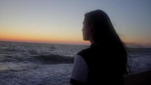 Flickan tittar på soluppgången på havet i rörelse — Stockvideo