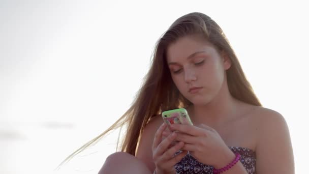 Ragazza adolescente utilizzando smartphone sulla spiaggia . — Video Stock