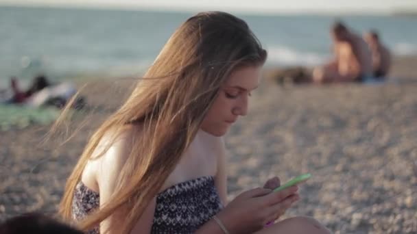 Дівчина-підліток використовує смартфон на пляжі . — стокове відео