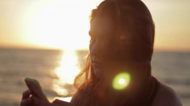 Sahilde Smartphone kullanan genç kız.